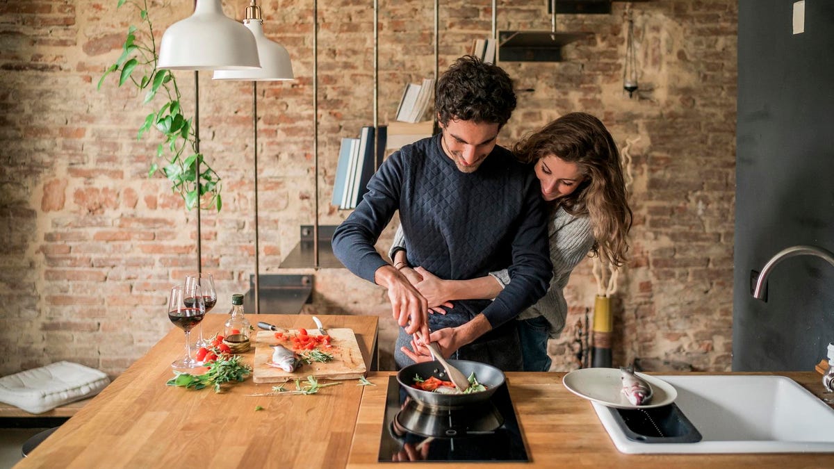 Young couple cooking fish cuisine at kitchen counter hob