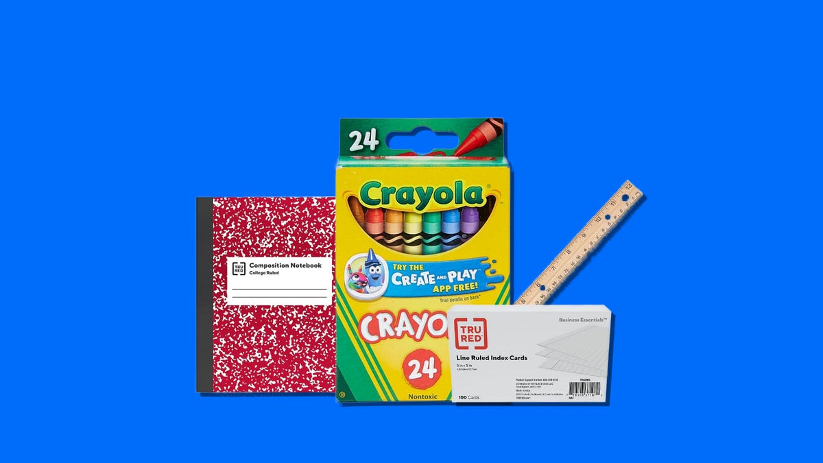 Crayola crayons, red composition book, index cards and a ruler on a blue background