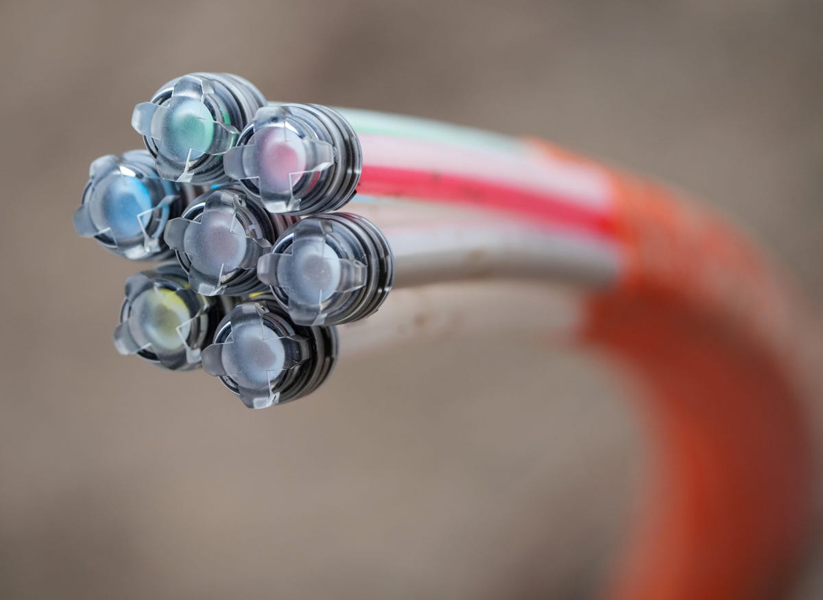 A fiber optic cable arcs toward the screen -- seven cables in one, all carrying light particles to speed up internet connections.