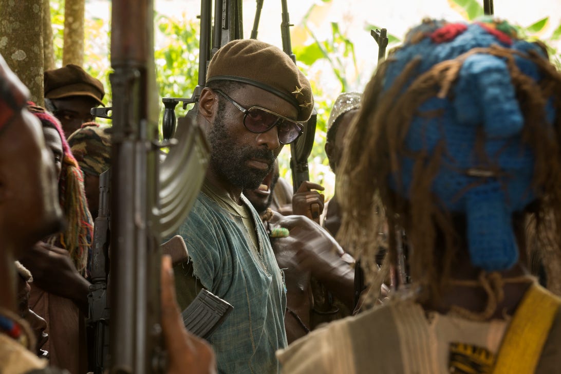 Actor Idris Elba stands as a warlord in a crowd of gun-toting soldiers in Beasts of No Nation