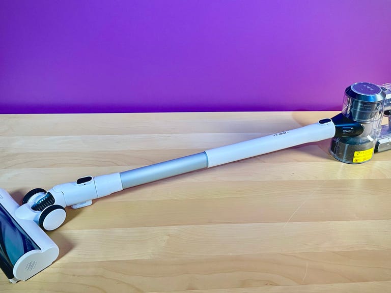 The Tineco Pure One S11 cordless vacuum sits atop a woodgrain table in front of a purple-colored background. It's CNET's top-recommended cordless vacuum of 2023.