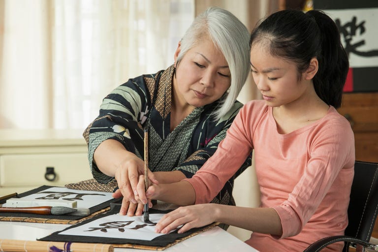 A Japanese woman instructs a young girl in calligraphy