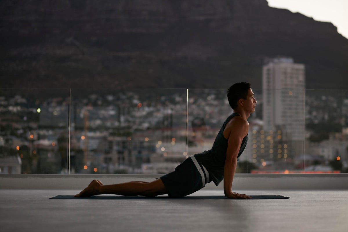Person doing a yoga pose outdoors with a city in the background