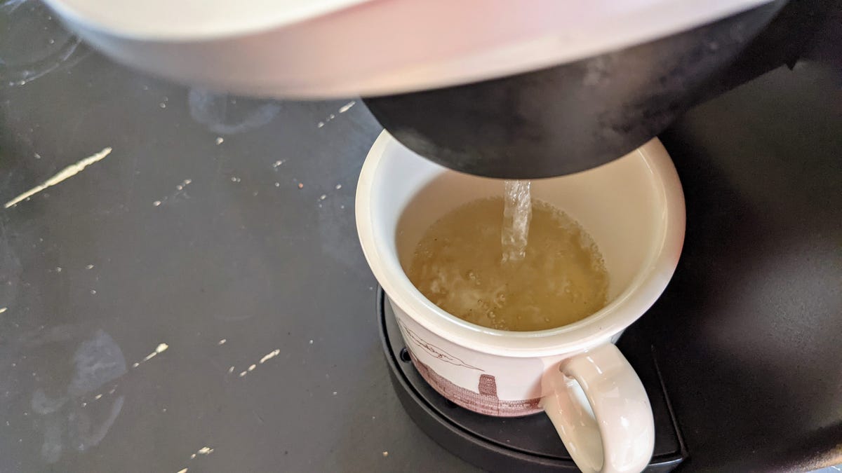 A Keurig filling a cup with brownish water