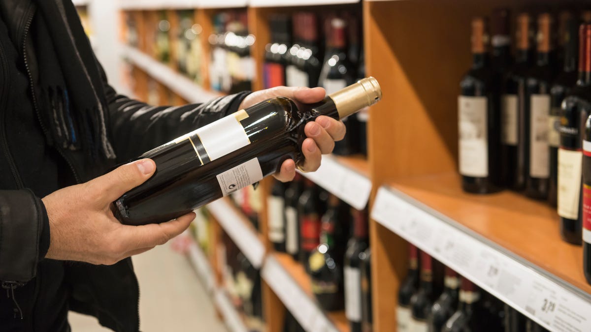 person holding bottle of wine in store