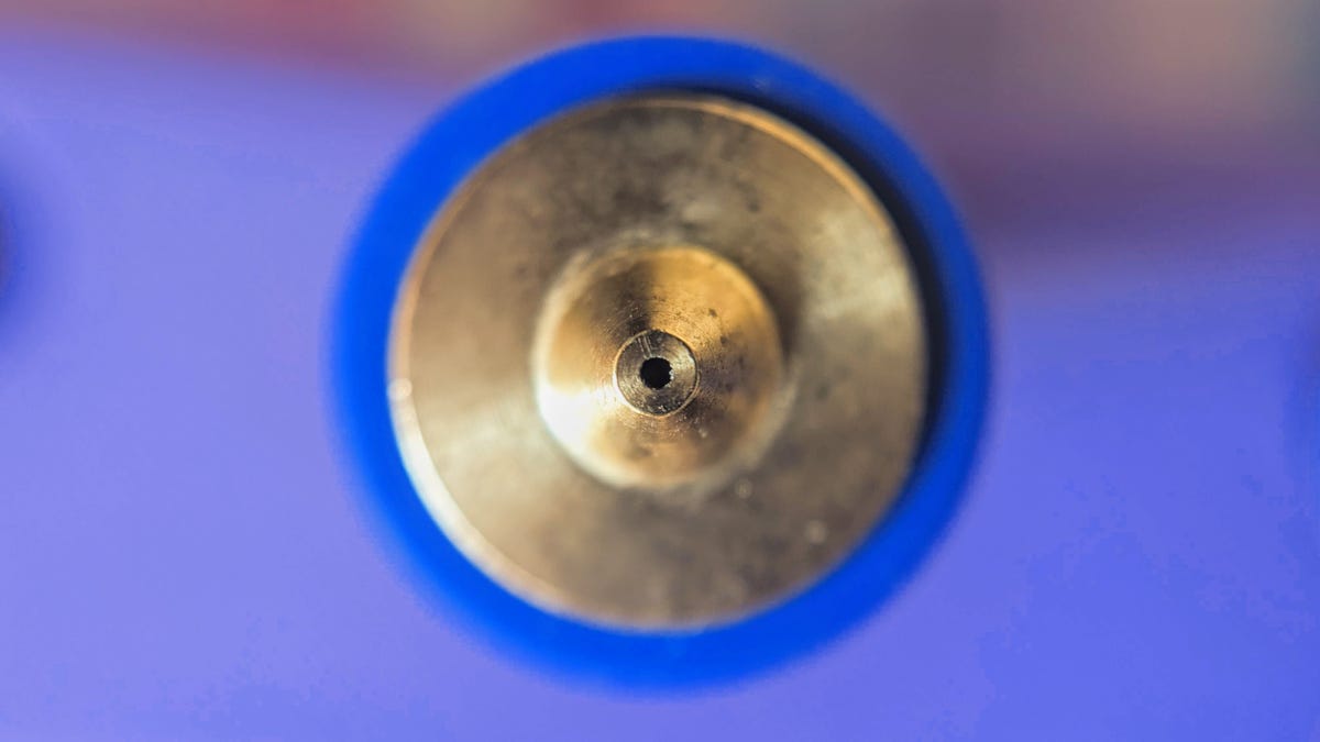 A brass nozzle close up, focused on the tip