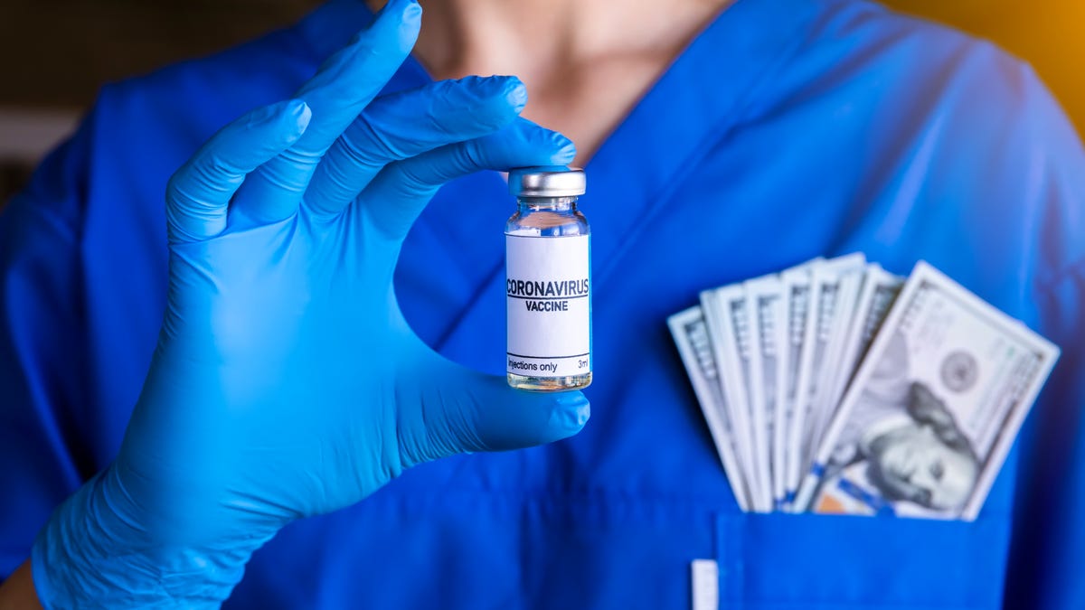 Health care worker holds vaccine vial with cash in their pocket.