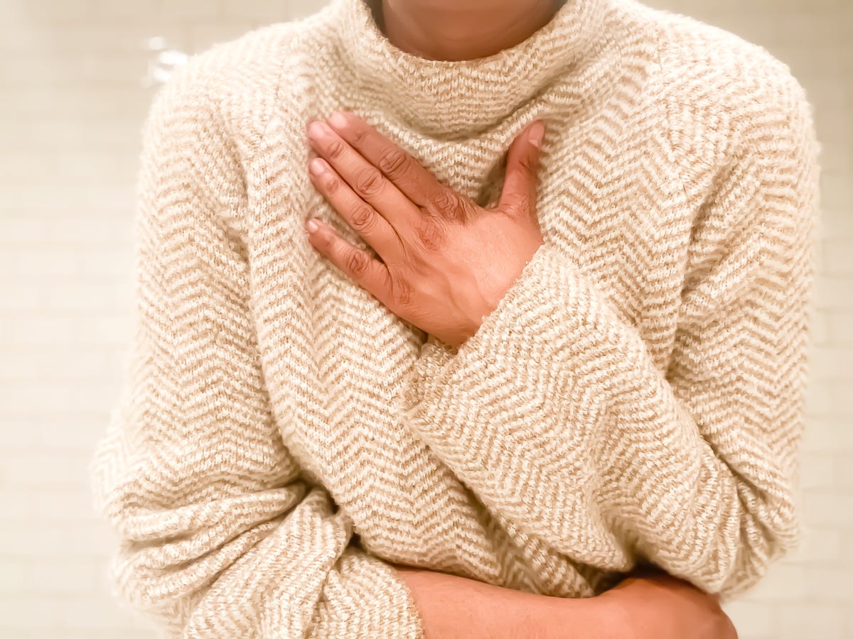 A person in a sweater clutches their chest.