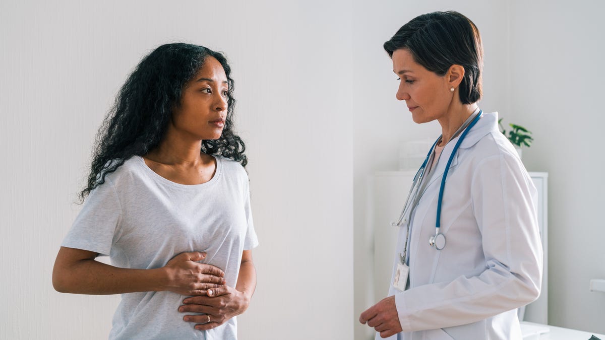 A woman experiencing abdominal pain discussing with her doctor