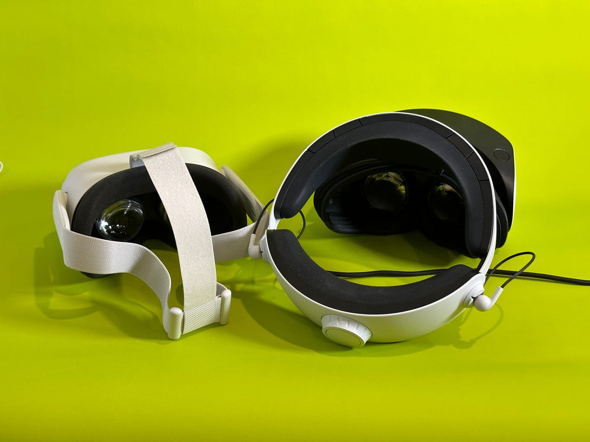 The back of two VR headsets, looking at the lenses, sitting on a green table
