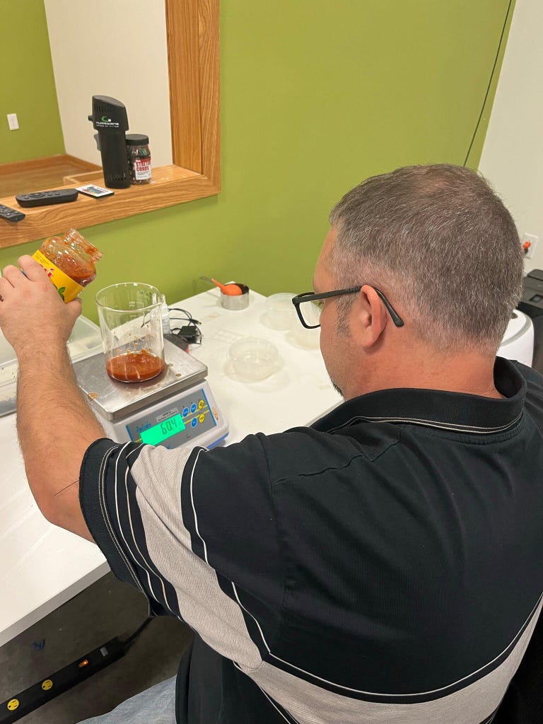 CNET lab associate Eric Snyder measures marinara sauce into a cup on a scale, ensuring the exact same amount is used for each tough mess test.