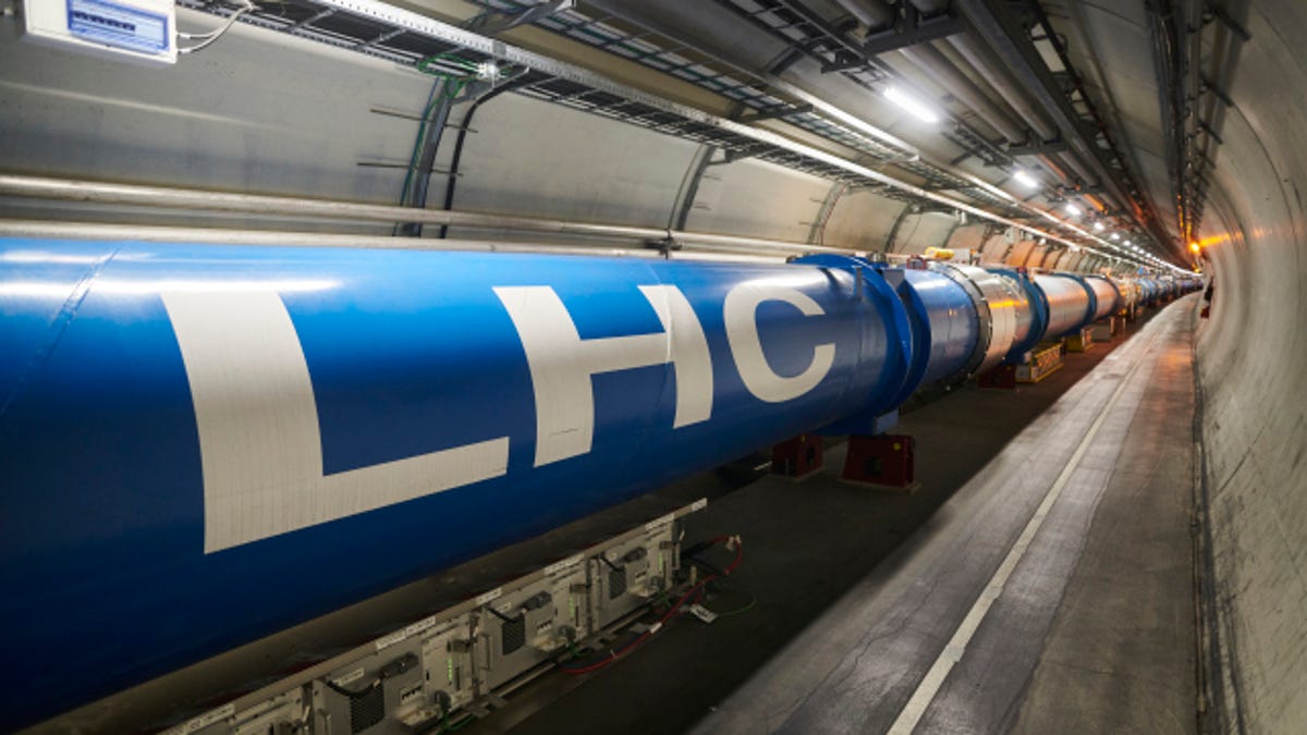 A blue section of CERN's Large Hadron Collider runs through a grey tunnel, with the letters "LHC" painted in white.