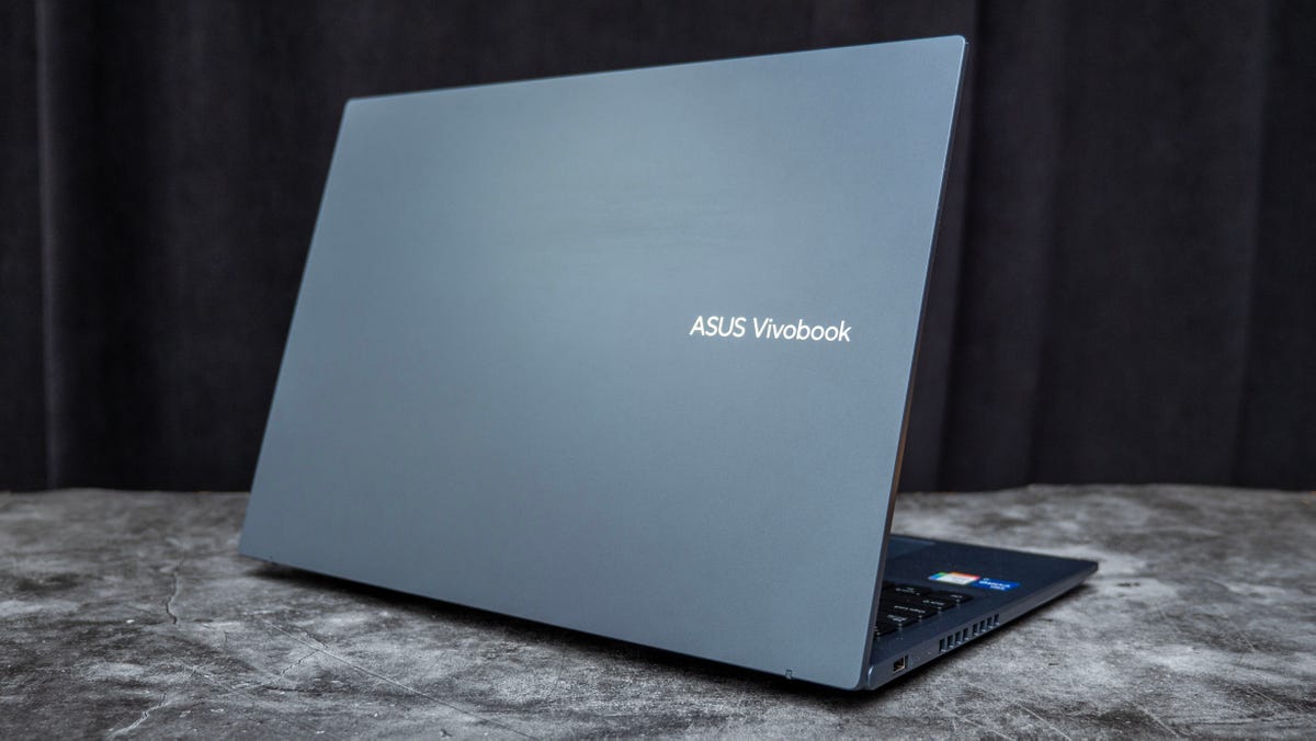 Asus Vivobook 16X OLED laptop open on a marble table with a black background.