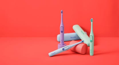 Several Colgate Hum toothbrushes against a red background.