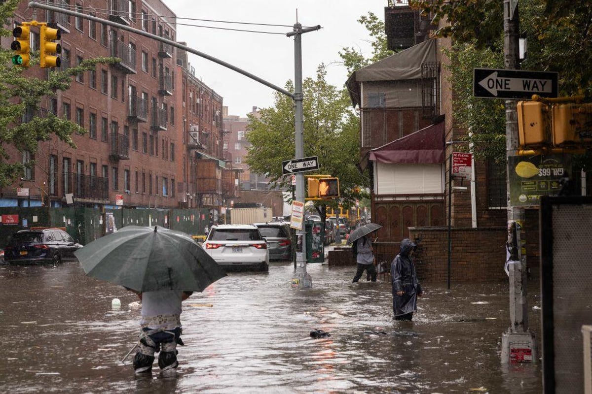 People wading through NYC flood water, which reaches above their knees