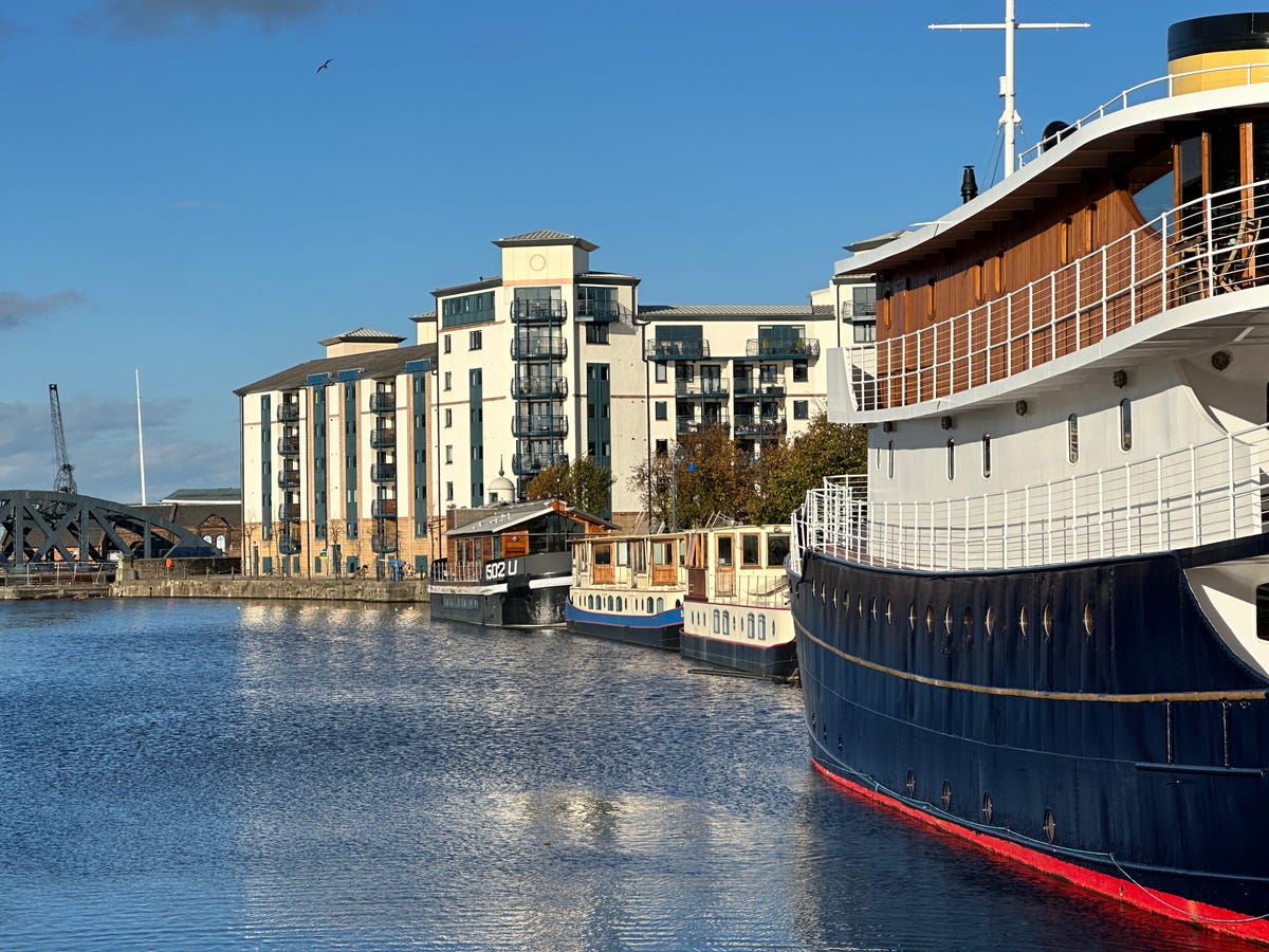 An image showing riverside buildings and moored narrowboats.
