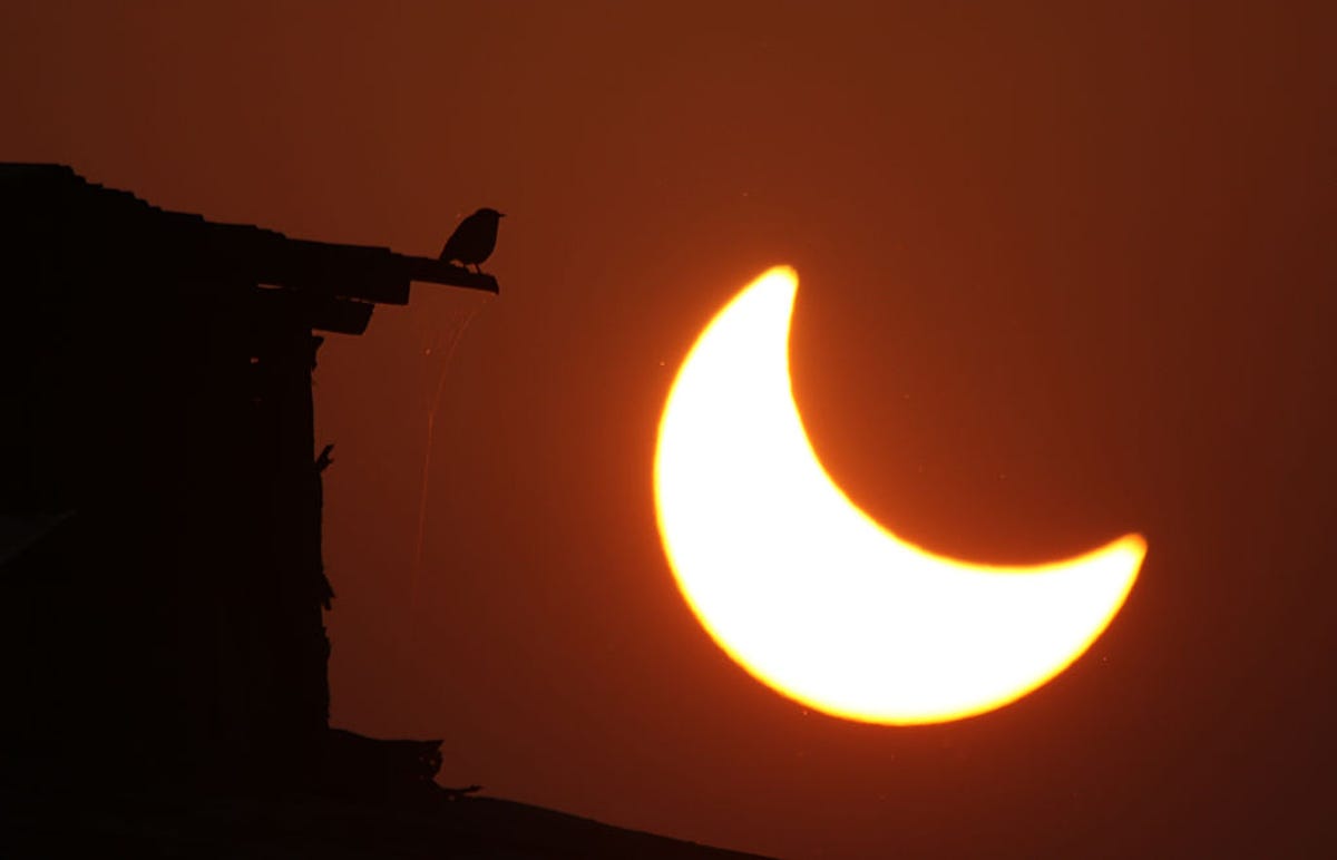 Glowing partial solar eclipse next to a building in Kashmir, India
