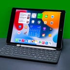 iPad van de 9e generatie met accessoires bevindt zich op een grijs oppervlak met een groene achtergrond.