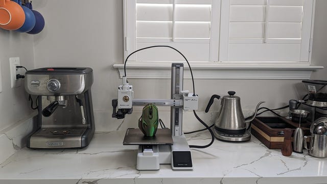 A 3D printer sat next to a kettle and a coffee machine