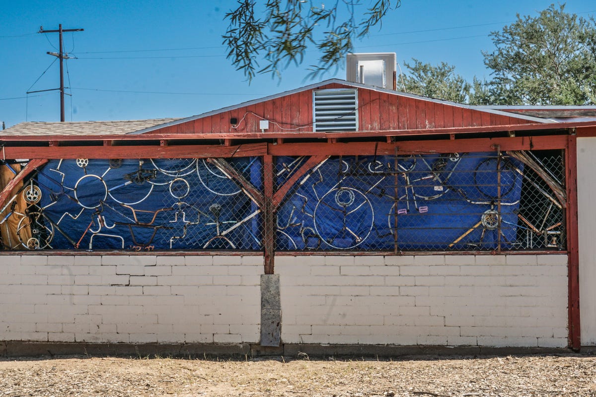 Uma parede externa de uma casa com muitas peças de bicicleta penduradas.