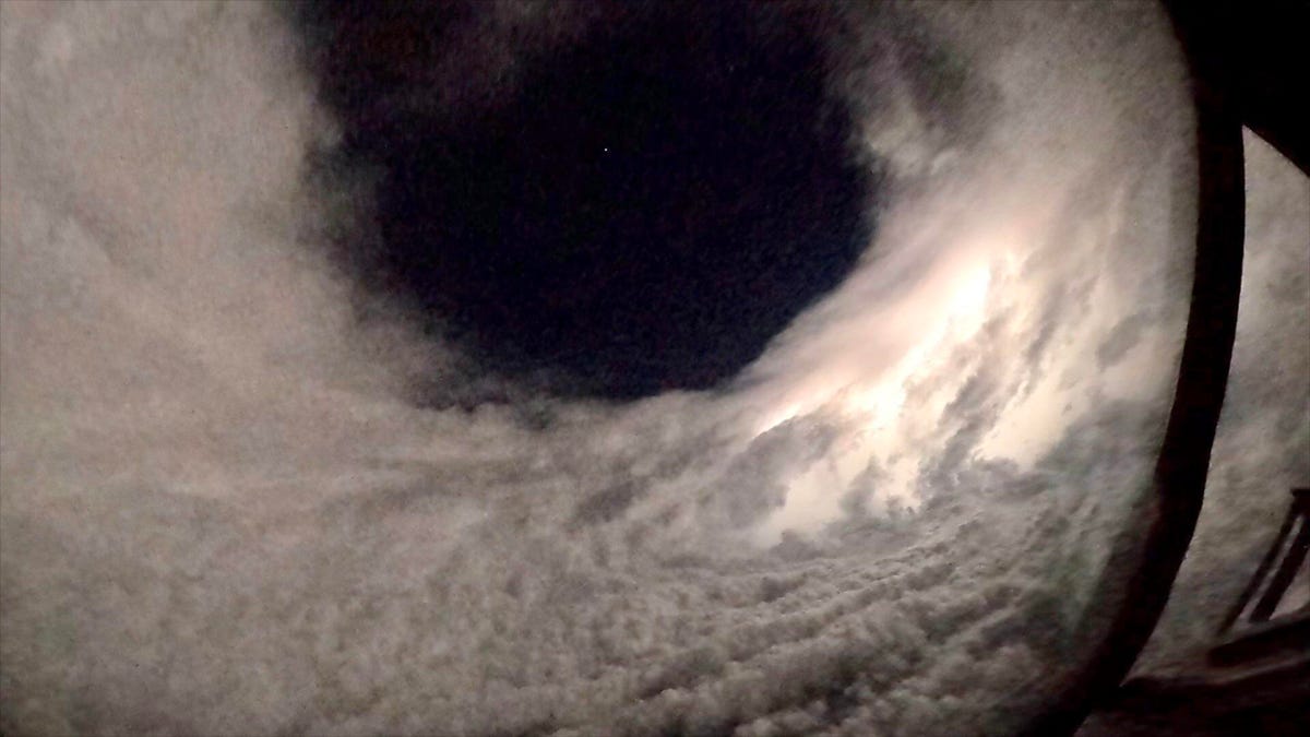 Downward view from a Hurricane Hunters airplane into Hurricane Lee shows a dark center and round tube of thick clouds.