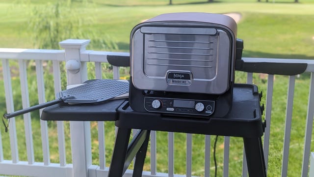ninja outdoor oven on a table with a golf course behind it
