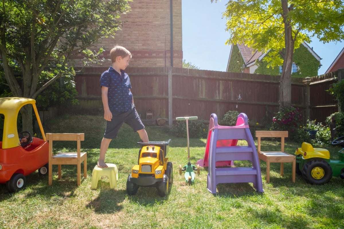 a young boy playing on an obstacle course made of toys in a yard