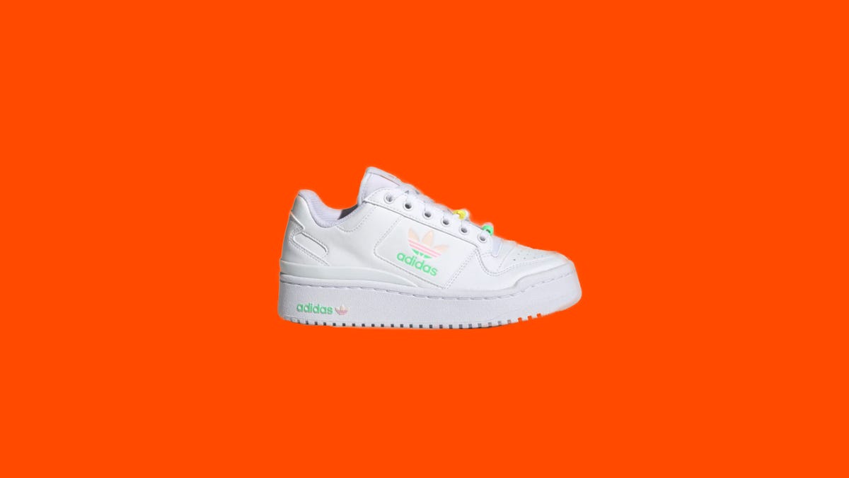 One white, pink and green kid shoe on an orange background