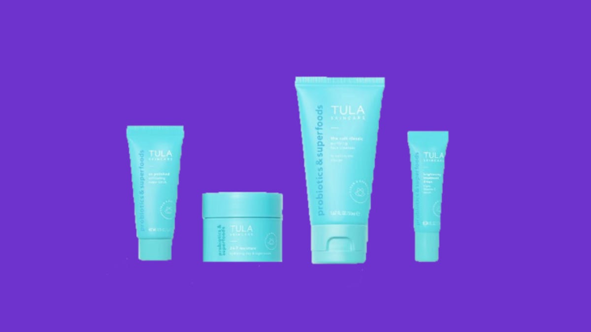 Four light blue bottles of Tula skin care products on a purple background