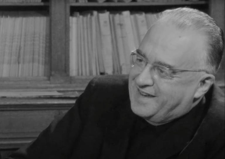 A black and white still from the found footage shows a close-up of Georges Lemaître sitting in front of a bookshelf.