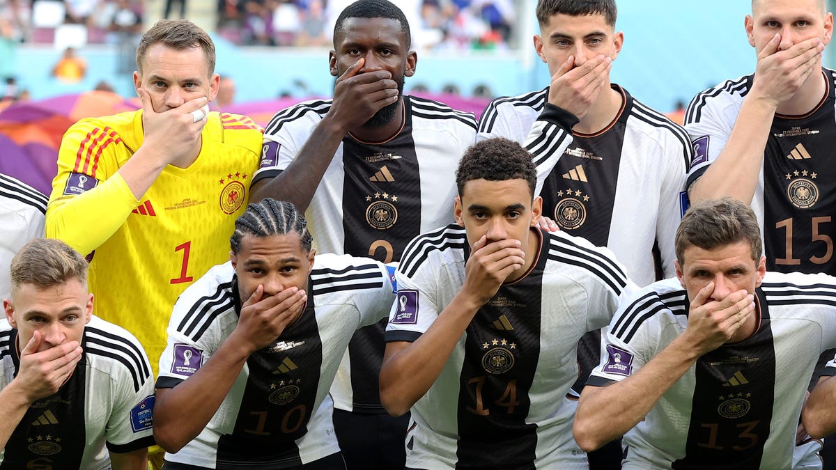 Germany's soccer players cover their mouths before a 2022 World Cup match.