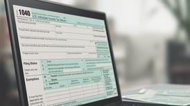 a black laptop computer showing an IRS Form 1040 tax form on its screen