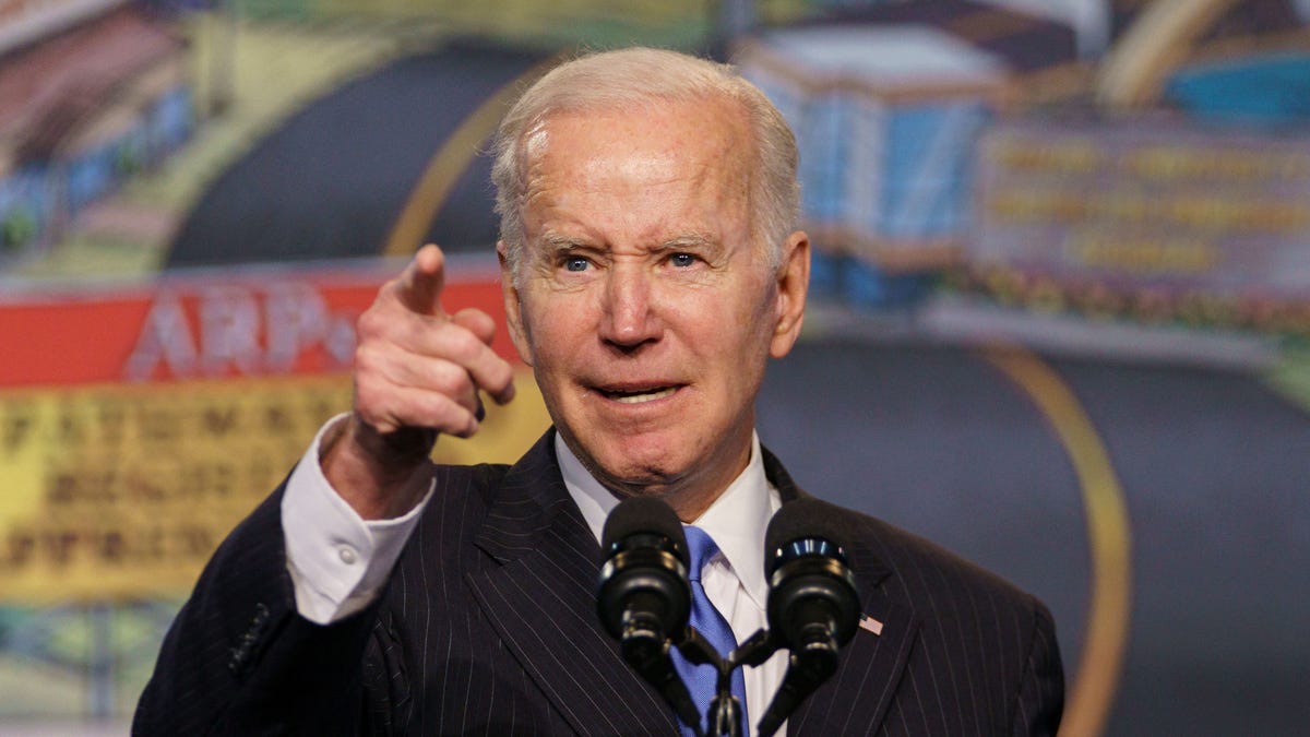President Joe Biden at a microphone, pointing with his right hand