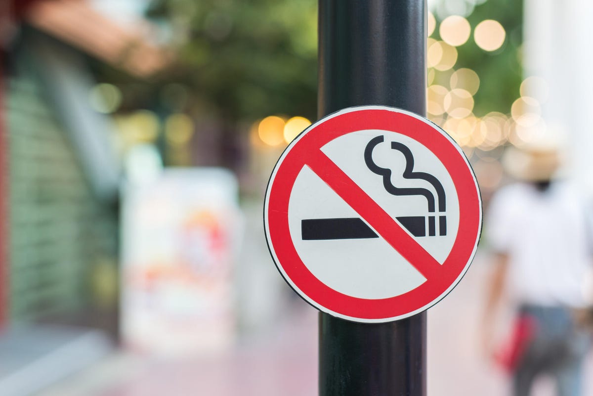 a no smoking sign on a street pole