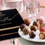 A box of Godiva truffles are displayed on a plate on a glass table.