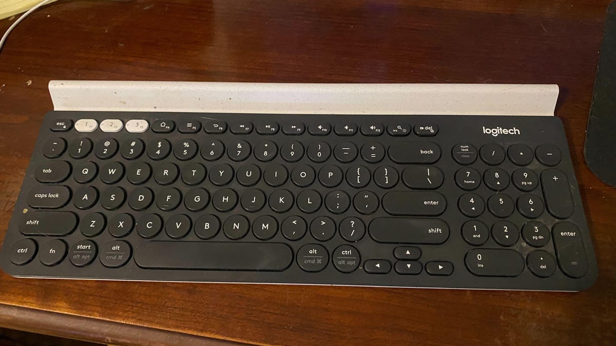 A black Logitech keyboard on a wooden desk.