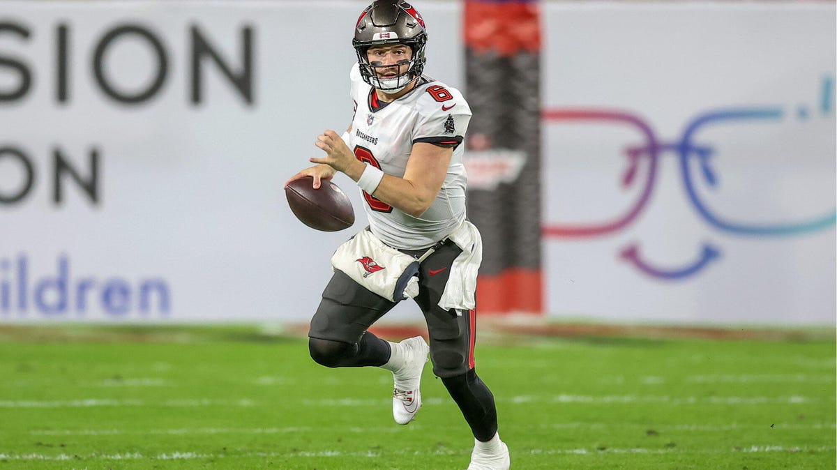 Baker Mayfield of the Tampa Bay Buccaneers running towards the camera with the ball in his right hand.