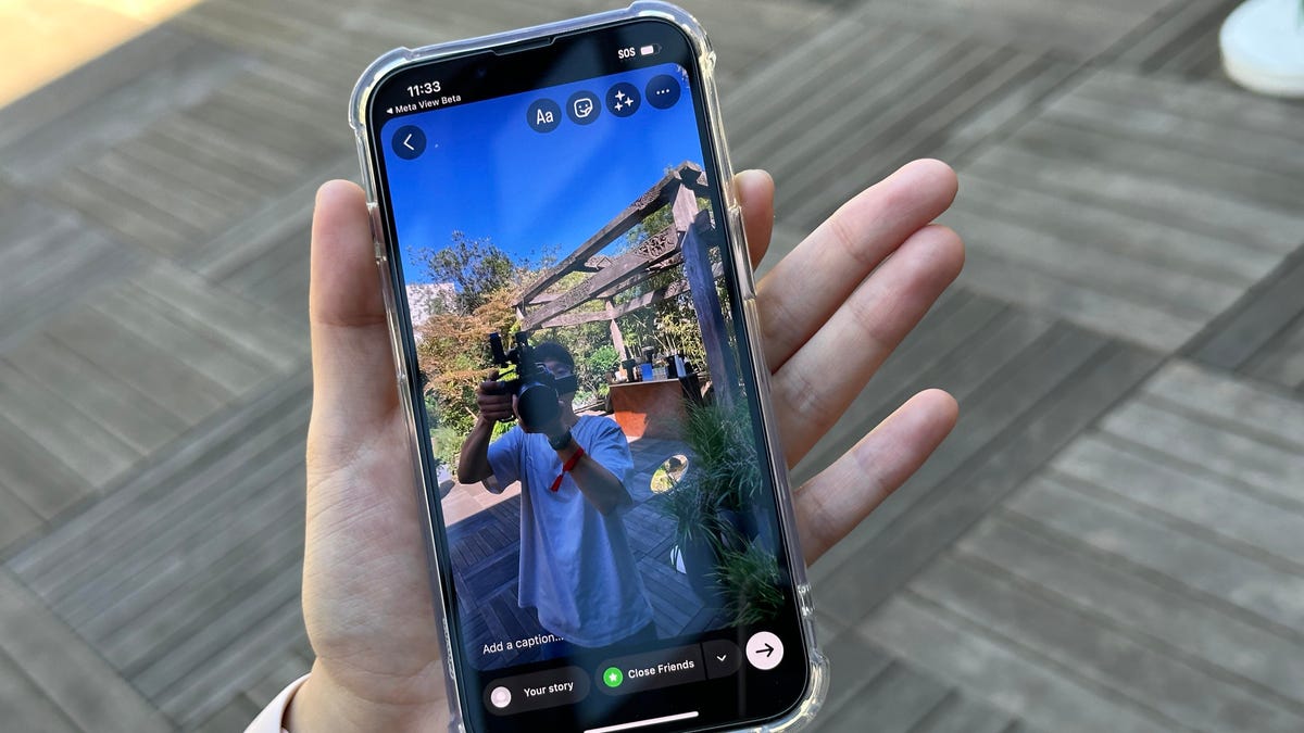 A hand holding a phone showing video where a camera person is recording us