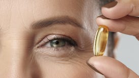 A middle aged woman hoping a fish oil pill next to her eye
