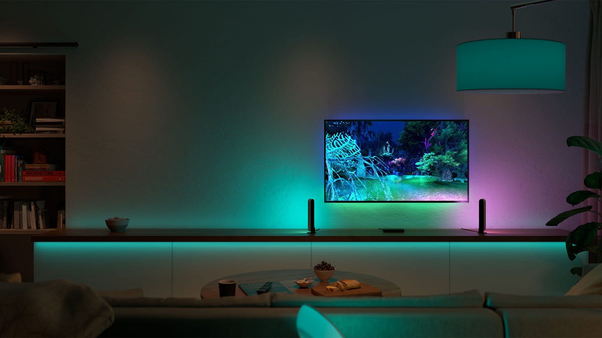 A living room dimly lit with green Philips Hue smart lights that match the TV screen colors.