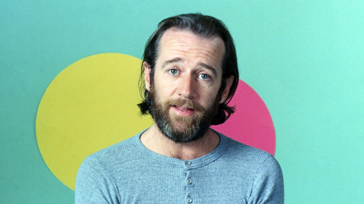 Comedian George Carlin in front of a colorful background.
