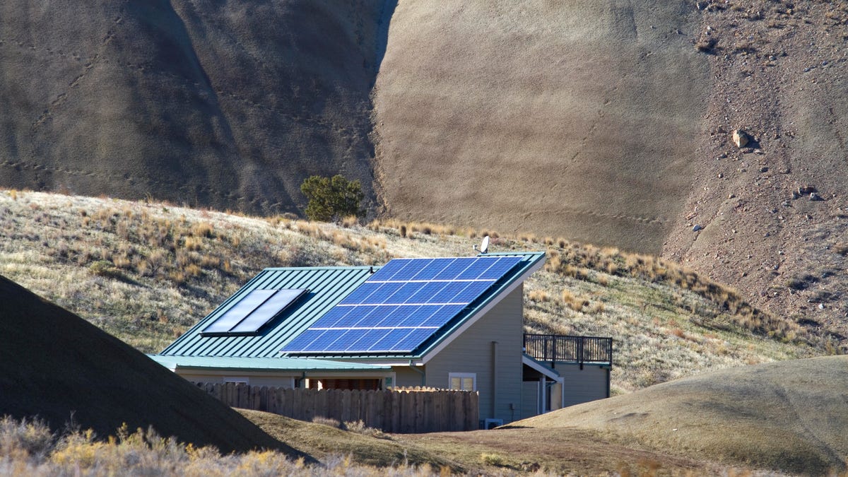 Rooftop solar panels in front of a desert cliff.