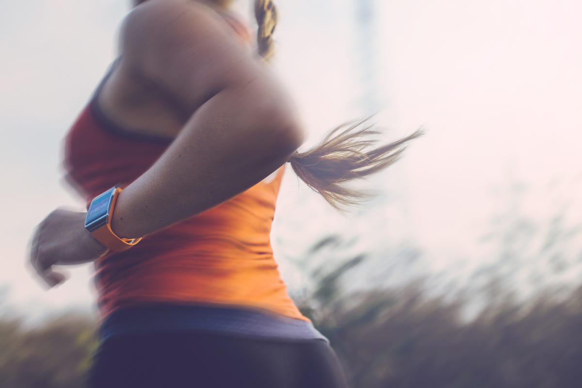 Torso of a woman running alone with her Apple Watch