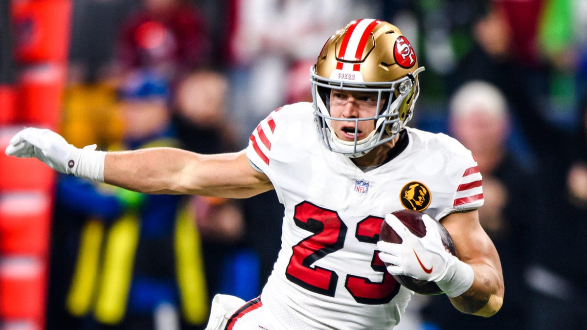 San Francisco 49ers running back Christian McCaffrey with his right hand extended while holding the ball under his right hand.