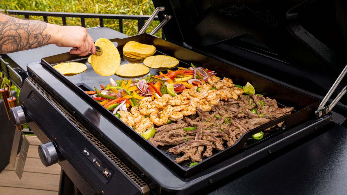 Close up of steak, shrimp, vegetables, and taco shells on a grill