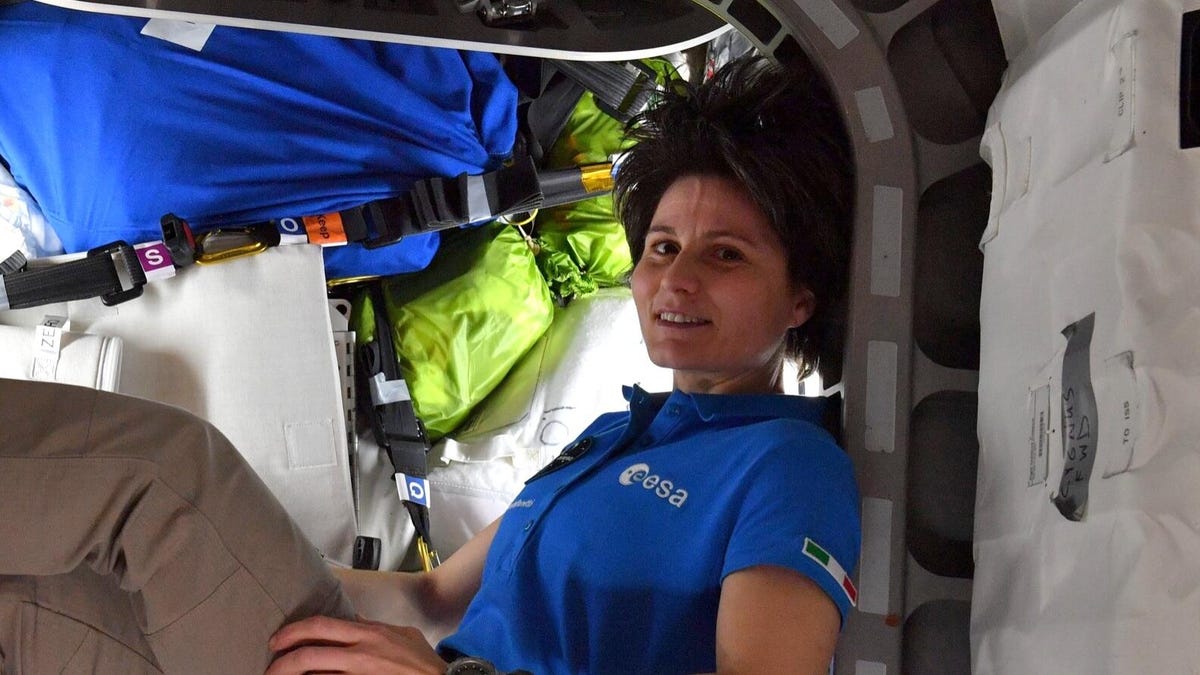 ESA astronaut Samantha Cristoforetti in a hatch to the Cygnus spacecraft with bags of garbage behind her.