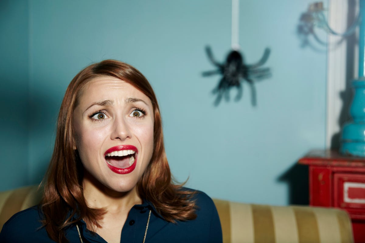 Woman looking at a spider in fear