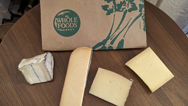 Four blocks of cheese in front of Whole Foods bag