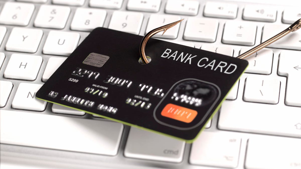 a picture of a credit card on a fish hook on top of a computer keyboard.