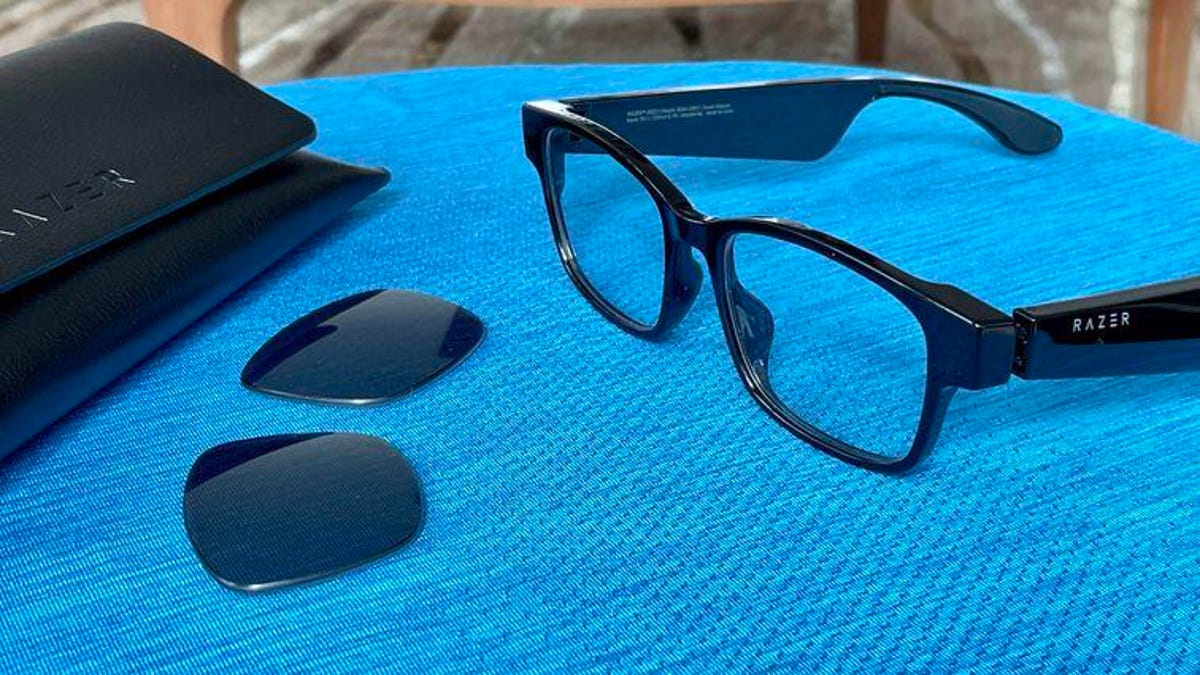 Razer Anzu glasses on a blue surface next to dark lenses and a case